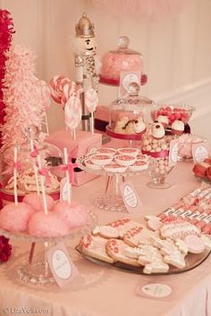 a table topped with lots of pink and white desserts