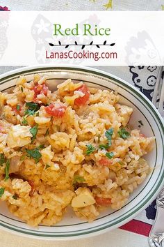 a white plate topped with rice covered in tomatoes and parsley next to silverware