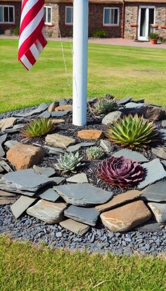 an american flag is in the middle of a rock garden with succulents