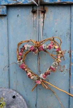 a heart shaped wreath hanging from the side of a blue door