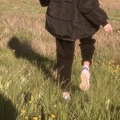 a person walking through tall grass with an umbrella over their head and one foot in the air