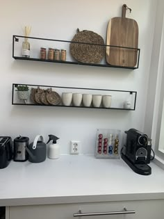 two black shelves above a counter with coffee cups and other items on top of it