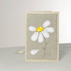 a card with a daisy on it sitting on a table next to a computer mouse