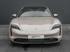 a white sports car parked in a parking lot next to a gray wall and black door