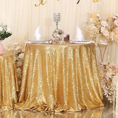 the table is covered with gold sequins and there are flowers in vases