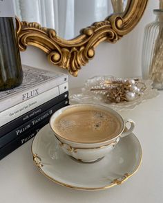 a cup of coffee sitting on top of a saucer next to a stack of books