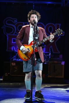 a man standing on top of a stage holding a guitar