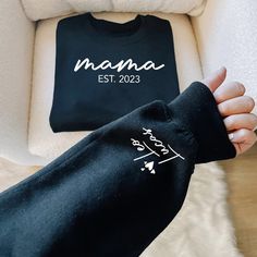 "Custom Mama Sweatshirt with Date and Childs Name on Sleeve, New Mom, Personalized Mom Hoodie, Minimalist Mom Sweater, Birthday Gift for Mom ----------- How to Order Your Custom Design T-shirt ---------- * Choose your t-shirt color * Choose your size * PLEASE make sure all your order's steps Please type: Only name(s) on the sleeve (For multiple names, please list commas between them) And please type Est. Year -The text on the chest and the hearts on the sleeve will be automatically added -Names are printed on one sleeve only For Example: Leo, Lucas Est. 2023 ---------- Product ---------- * 4.2 oz., 100% airlume combed and ringspun cotton, 32 singles * 32 singles Athletic Heather and Black Heather are 90/10 airlume combed and ringspun cotton/polyester Ash is 99/1 airlume combed and ringspun Black Hooded Sweatshirt Gift, Black Hooded Sweatshirt As Gift, Black Long Sleeve Sweatshirt With Custom Text, Mother's Day Black Crew Neck Sweatshirt, Black Long Sleeve Sweatshirt With Name Print, Mother's Day Sweatshirt With Custom Text, Casual Black Sweatshirt For Birthday, Black Casual Sweatshirt, Casual Black Sweatshirt For Mother's Day