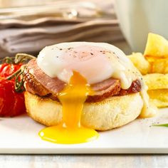 a breakfast sandwich with an egg on top and french fries next to it, sitting on a white plate