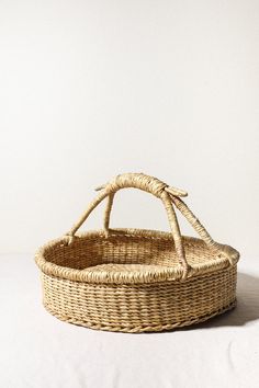 an empty wicker basket with handles on a white surface