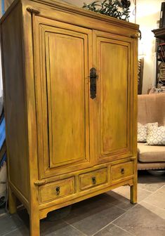 an old yellow armoire is sitting on the floor next to a couch and coffee table