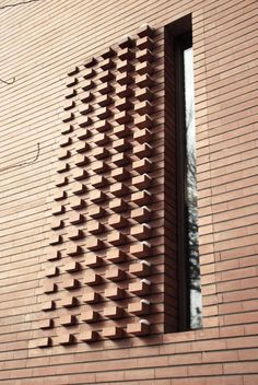 the side of a brick building with an open window on it's side, made out of bricks