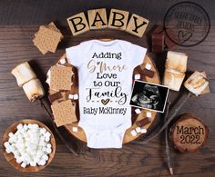 a baby bodysuit is surrounded by cookies and marshmallows