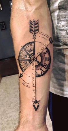 a man's arm with a compass tattoo on it and an arrow in the middle