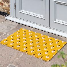 a yellow door mat sitting on top of a stone floor next to a white door