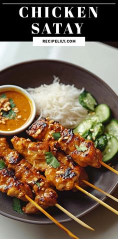 chicken satay on a plate with rice and cucumber garnishes