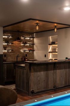 a pool table and bar in a room with lights on the ceiling, along with an entertainment center