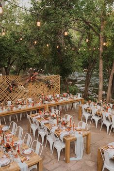 an outdoor dining area with tables and chairs set up for a wedding reception in the woods