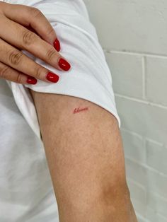 a woman's arm with the word mom written on it and red nail polish