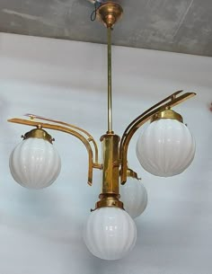 an antique brass chandelier with three white glass globes hanging from the ceiling