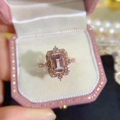 someone is holding an engagement ring in a box with pearls on the sides and a pink diamond center stone