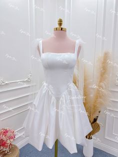 a white dress is displayed on a mannequin in front of a wall with feathers