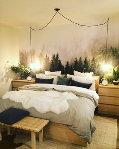 a bed with pillows and blankets on top of it in front of a forest mural