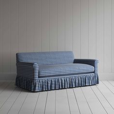 a blue and white checkered couch sitting on top of a hard wood floor next to a wall