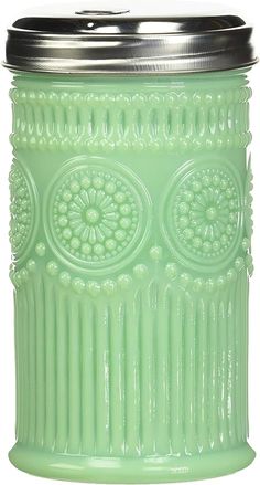 a green glass jar with an ornate design