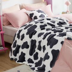 a cow print blanket on top of a bed