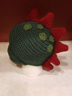 a crocheted green and red hat on top of a white mannequin head