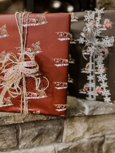 two wrapped presents sitting on top of a stone fireplace