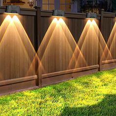 a fence that has some lights on it and grass in front of the fence,