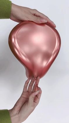 two hands holding a pink heart shaped balloon