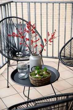 a small table with a basket and vase on it, sitting on a tiled patio