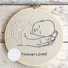 a hand embroideryed picture with the words forever loved and an image of a woman holding a baby in her arms