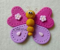 a pink and purple butterfly brooch sitting on top of a white surface