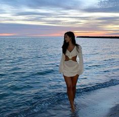 a woman walking on the beach at sunset