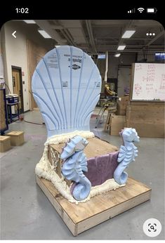 a large blue shell chair sitting on top of a wooden platform