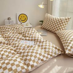 a bed with checkered sheets and pillows on top of it next to a window