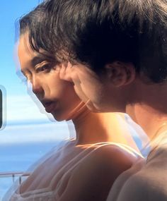 two women looking at each other through a window with the ocean in the back ground