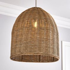 a wicker light fixture hanging from a ceiling in a room with white walls and trimmings