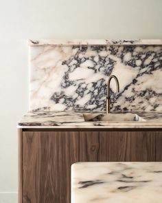 a marble sink and counter top in a kitchen with white walls, wood cabinets and flooring