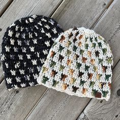 two crocheted hats sitting on top of a wooden table next to each other