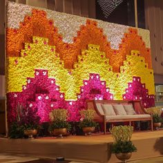 a large flowered wall in the middle of a room with couches and potted plants