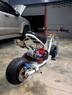 an electric scooter is parked next to a car in a garage with no wheels