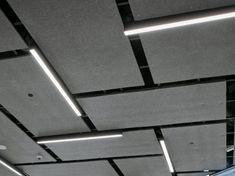 the ceiling is covered in black and white tiles, with square lights above it that are suspended from the rafters