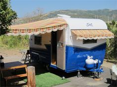 a blue and white trailer parked next to a picnic table