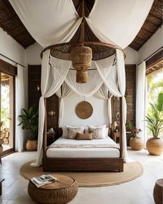 a bedroom with a canopy bed and wicker furniture on the floor in front of large windows