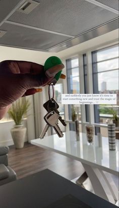 a hand holding keys in front of a window